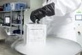 A laboratory specialist removes products from a cryogenic storage drawer.