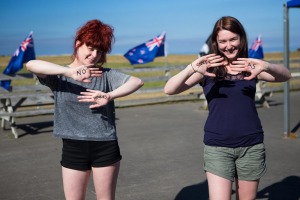 Girls write traditional Kiwi greetings on their hands in New Zealand.
