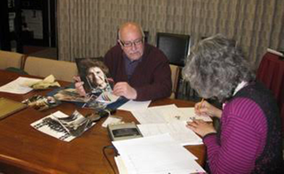 March 1, 2011, with tape recorder running, and Suzanne Adams, Archivist, taking the photo, Tom shares a photo he took of his mother, Ojen “Jennie” Hekimian Vartabedian, and shares her accomplishments as a Genocide Survivor with Ruth.