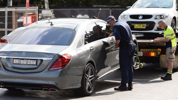 Police remove several luxury cars from an apartment building on Australia Avenue in Olympic Park.