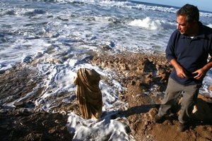 An Israeli man stands next to a 1,700-year-old statue after it was found on the beach in the costal city of Ashkelon, Tuesday, Dec. 14, 2010.