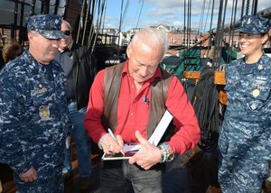 File - Retired astronaut Buzz Aldrin autographs a photo for Cmdr. Sean Kearns, the 73rd commanding officer of USS Constitution, left, and Command Senior Chief Nancy Estrada during a tour of USS Constitution, Charlestown, Mass.