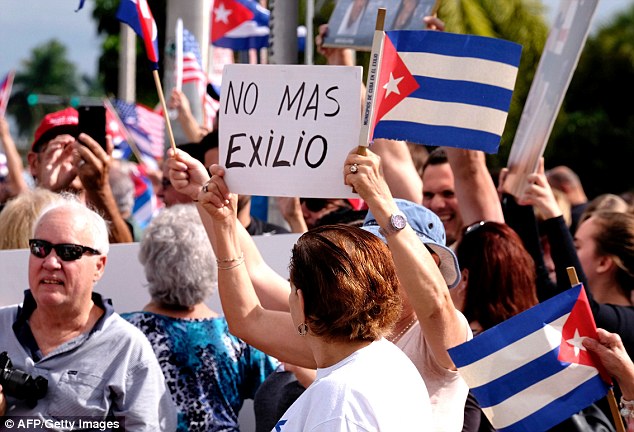 A woman holds up a sign saying 'No more exile' during the celebrations. In the 1960s and the 1980s, hundreds of thousands of Cubans left Cuba for America