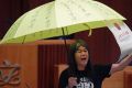 Elected pro-democracy lawmaker Leung Kwok-hung, known as "Long Hair," holds a yellow umbrella and a oversised mock copy ...