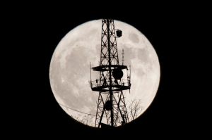 The moon rises behind a communication antenna tower in Sarajevo, Bosnia