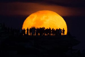 The moon rises above Ben Buckler point at Bondi, Sydney, a day after the official supermoon which was obscured by ...