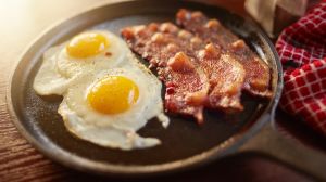 fried bacon and eggs in iron skillet shot with selective focus