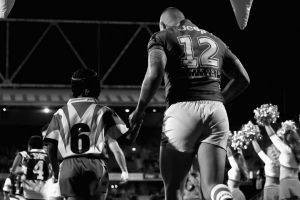 Just what is the game? Joel Thompson of the Dragons runs out with a local junior footballer during a match last season.