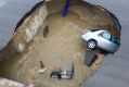The sinkhole swallowed two cars, leaving one woman dead. 