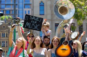 Supporters pose for photographs at the Melbourne Busk Protest against Radio National program cuts at Federation Square.