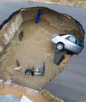 The sinkhole swallowed two cars, leaving one woman dead. 