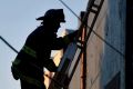 A firefighter climbs a ladder after a deadly fire at a warehouse rave party in Oakland, California.