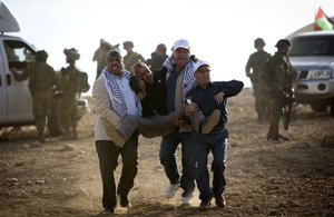 File - Palestinian activists carry a wounded man after clashes with Israeli soldiers during a demonstration against the construction of Jewish settlements in the Jordan Valley, in the West Bank, Thursday, Nov. 17, 2016.