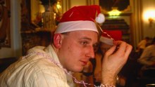 A close shot of a man looking melancholy and wearing a santa hat.