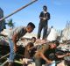 People search for usable items in the rubble of a building that collapsed during Wednesday's earthquake in Trienggadeng, ...