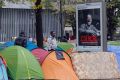 Migrants stand next tents in a makeshift camp in Paris.