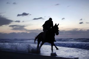 A Palestinian man rides a horse on the beach as the sun sets over Gaza city, Thursday, Nov. 17, 2016.
