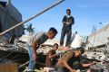 People search for usable items in the rubble of a building that collapsed during Wednesday's earthquake in Trienggadeng, ...