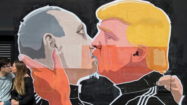 A couple kisses in front of graffiti depicting Vladimir Putin, left, and Donald Trump, on the walls of a bar in the old ...
