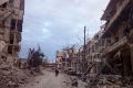 Men walk past damaged buildings and shops in the eastern Aleppo neighborhood of al-Mashhad.