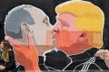 A couple kisses in front of graffiti depicting Vladimir Putin, left, and Donald Trump, on the walls of a bar in the old ...