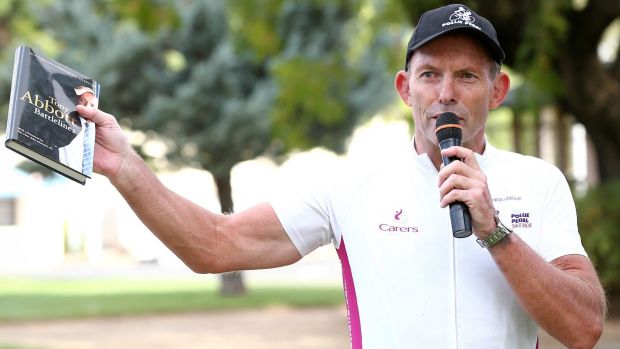 Former prime minister Tony Abbott holds up a copy of his book <i>Battlelines</i> in Forbes during the 2016 Pollie Pedal tour.