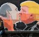 A couple kisses in front of graffiti depicting Vladimir Putin, left, and Donald Trump, on the walls of a bar in the old ...