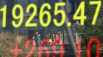 People are reflected on an electronic stock indicator of a securities firm in Tokyo on Monday, Dec. 12, 2016. (AP / Shizuo Kambayashi)