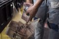 A fruit seller keeps 100-bolivar notes in a grocery bag at a fruit stand in Caracas on Monday.