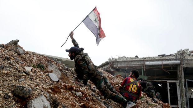 A Syrian army soldier places a Syrian national flag during a battle with rebel fighters at the Ramouseh front line, east ...