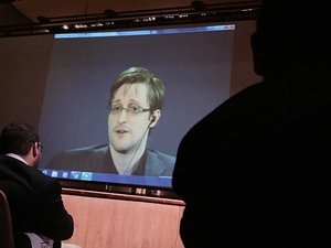 Former National Security Agency contractor Edward Snowden, center speaks via video conference to people