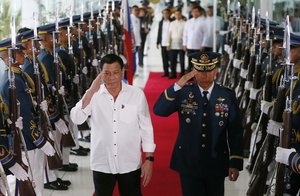 Philippine President Rodrigo Duterte salutes the honor guard prior to his departure for Cambodia and Singapore for official visits to the ASEAN neighbors, Tuesday, Dec. 13, 2016 at the Ninoy Aquino International Airport in suburban Pasay city south of Manila, Philippines.