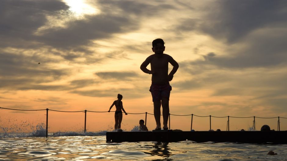 A young boy prepares to dive into the water at Bronte Baths a rock pool at Bronte Beach in the early morning before the ...