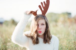 Silly teen girl in fuzzy white sweater wearing reindeer antlers For Daily Life: mini trend/christmas dress