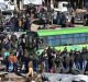 In this photo released by the Syrian official news agency SANA, residents gather near a green government bus for ...