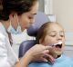 A dentist shows a child how to brush her teeth.