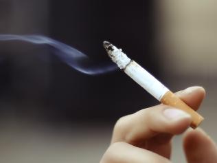 Cigarette in someones hand . smoke . iStock