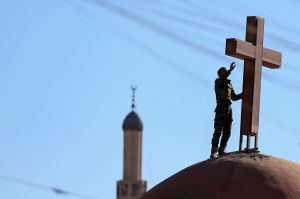 An Iraqi Kurdish Muslim Peshmerga fighter sets a cross on top of a church, which was damaged by Islamic State fighters ...