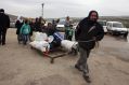 A Syrian man pulls belongings as he is evacuated with his family from Aleppo