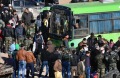 Residents gather near a green government bus for evacuation from eastern Aleppo.