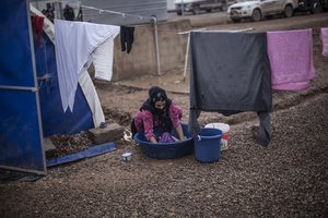 An Iraqi woman washes clothes in Khazer camp for the displaced, Iraqi Kurdistan, Iraq, Saturday, Dec. 17, 2016.