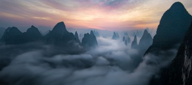 A view of the many karst mountains peaking through a river of fog. Taken on spring morning in Guangxi, China.