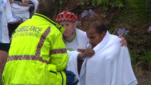 An ambulance officer comforts cyclists after a woman was killed on Mona Vale Road, Pymble.