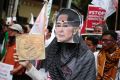 A Muslim woman wears a mask of Myanmar's Foreign Minister Aung San Suu Kyi during a rally against the persecution of ...