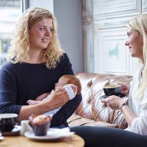 Caregiver using the Gro-hush to soothe her infant whilst out in a cafe