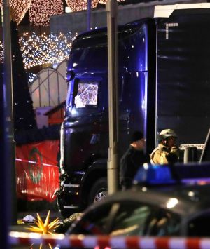 Police stand beside a damaged truck which ran into crowded Christmas market in Berlin.