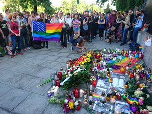 Two men with a banner in solidarity with the victims of the 2016 Orlando nightclub shooting running ahead of the main parade