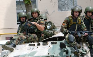 Heavily armed Chechen OMON, riot police, officers sit atop an APC near a dilapidated apartment building in the capital Grozny, on Tuesday, July 8, 2008, where a suspected Islamic militant was killed in a gunbattle.