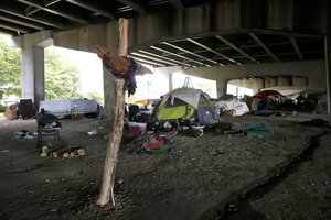 A makeshift cross sits firmly planted in the ground beneath an Interstate 30 overpass where many of the city's homeless have set up tents for housing, Saturday, Sept. 10, 2016, in Dallas.