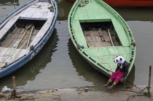A child wearing panda styled hat sits on a docked boat at Dashasumedh ghat on the banks of the Ganges river in Varanasi, ...
